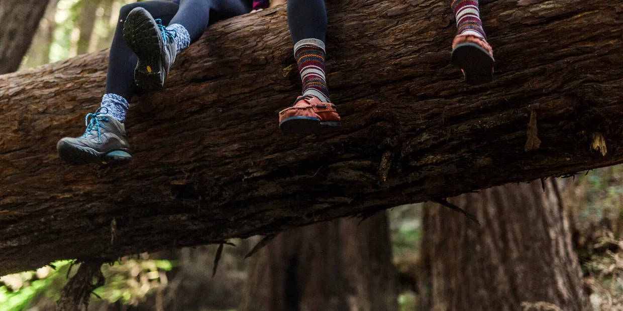 Folded merino wool hiking socks for women resting on a wooden surface beside hiking boots