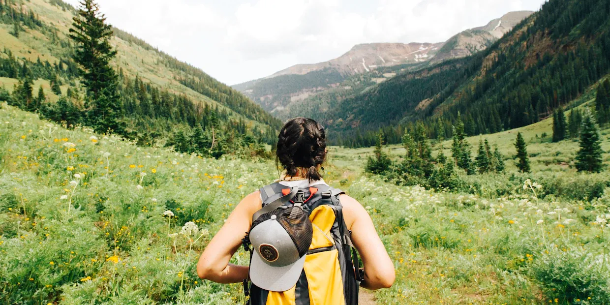 A hiker wearing a 20-liter daypack looking out over a mountain valley