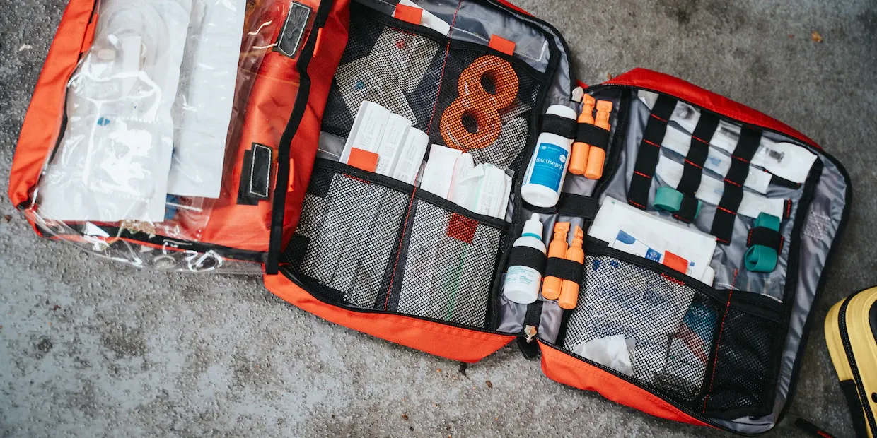 An open hiking first aid kit with bandages, gauze, and supplies laid out on a trail